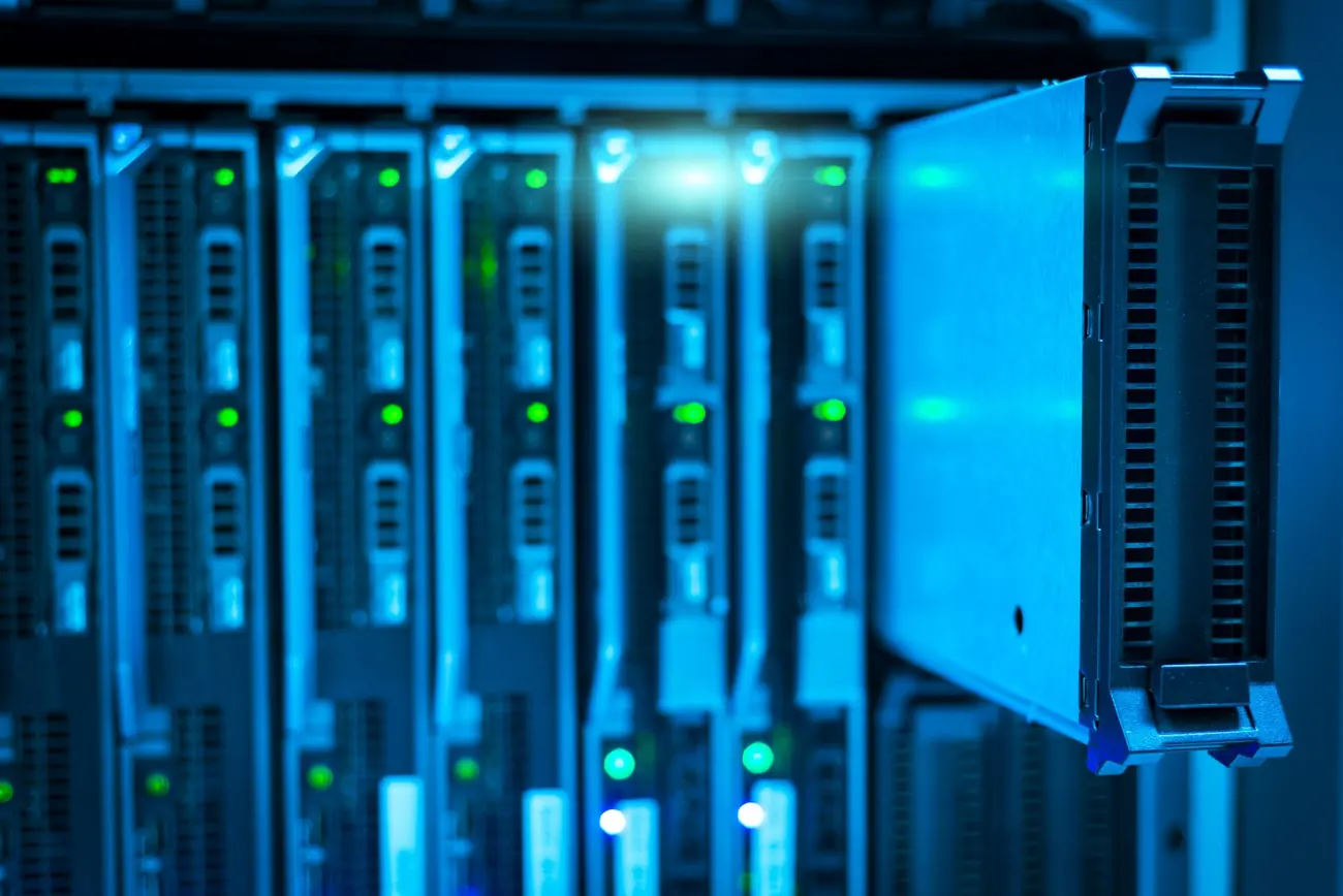 Primo piano di server a lama in un rack illuminati di luce blu con spie verdi.