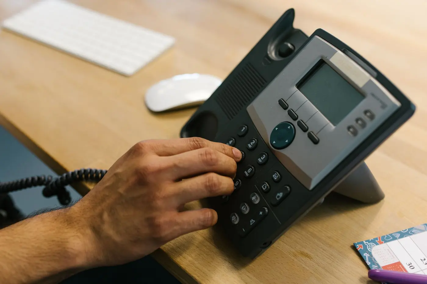 Mano che compone un numero su un telefono IP da scrivania