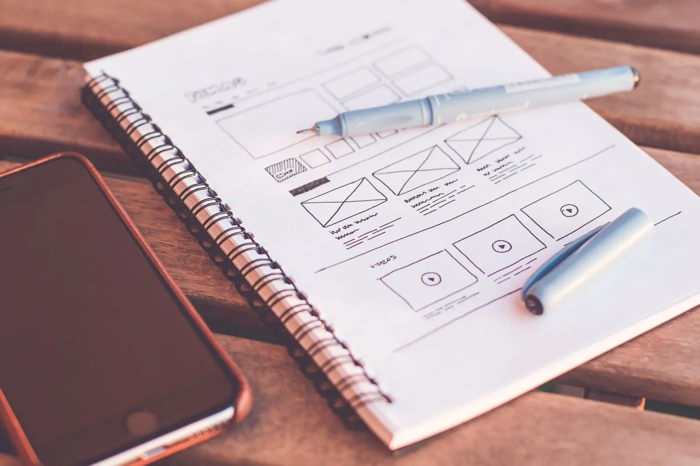 Quaderno con schizzi di un layout accanto a uno smartphone spento