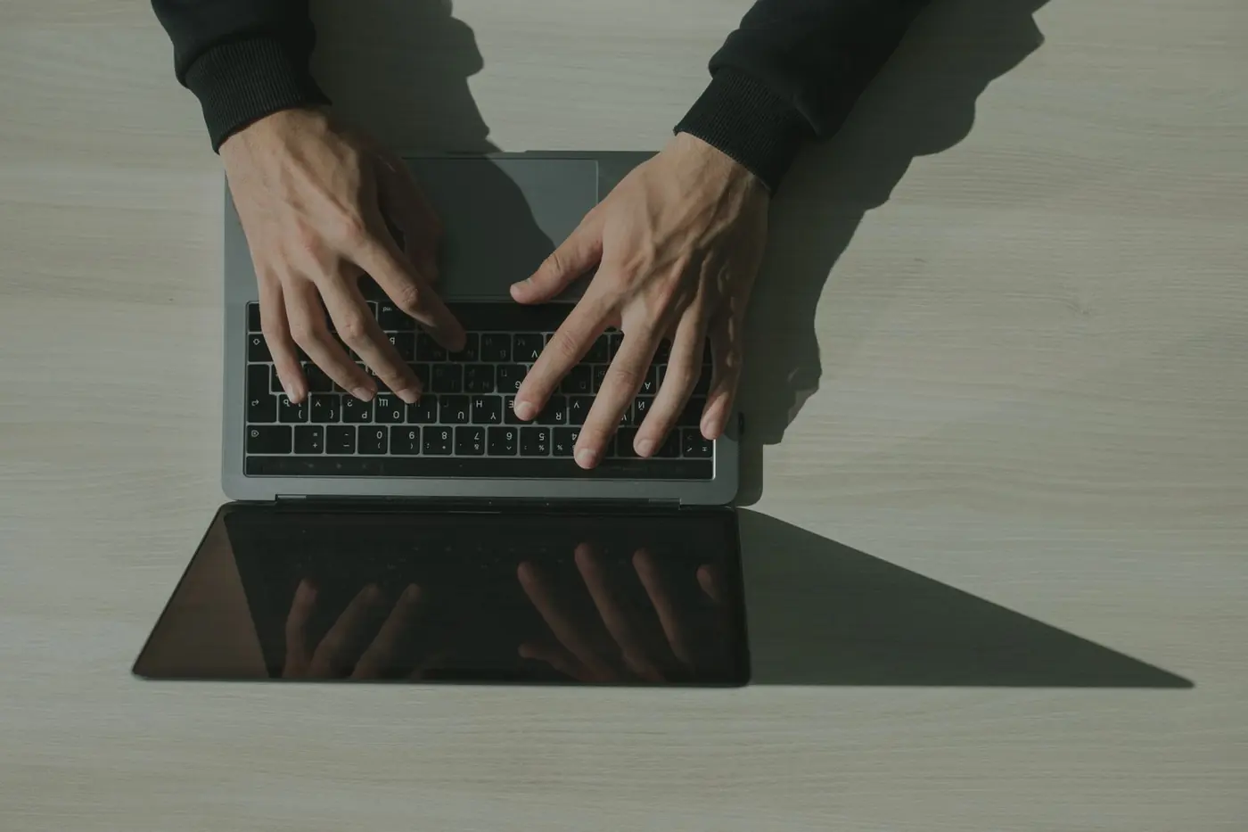 Mani che scrivono sulla tastiera di un portatile, viste dall'alto