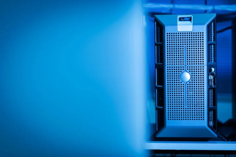 Server tower in metallo forato illuminato di luce blu in una sala server, con ampio spazio vuoto azzurro a sinistra.