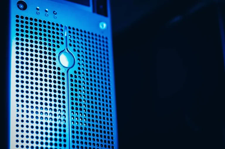 Primo piano del frontale forato di un server illuminato di blu su sfondo scuro in un data center.