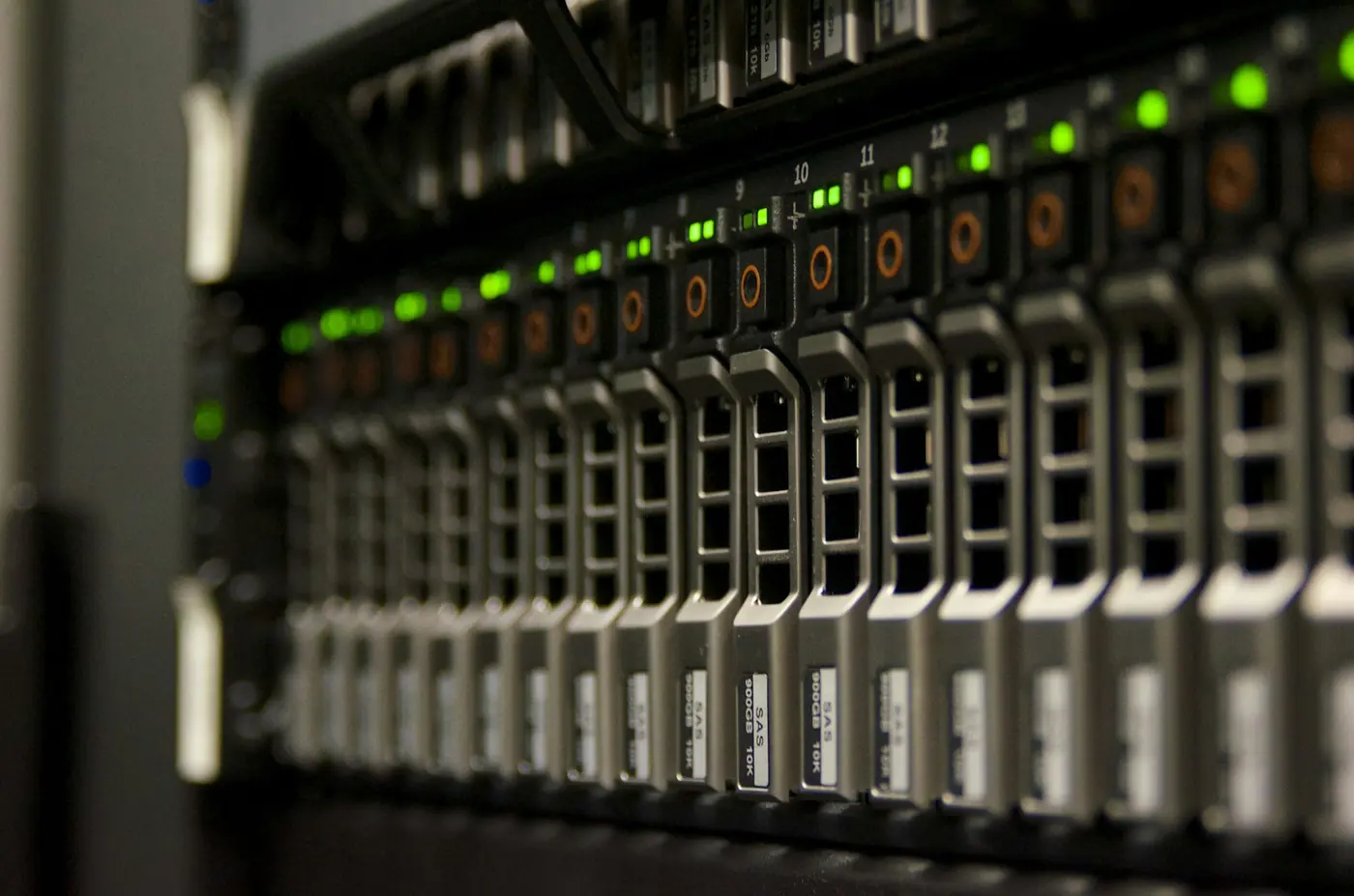 Rack server con vassoi disco e spie verdi lampeggianti, a fuoco ridotto.