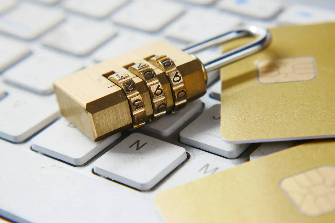Lucchetto a combinazione dorato su una tastiera bianca con carte con chip