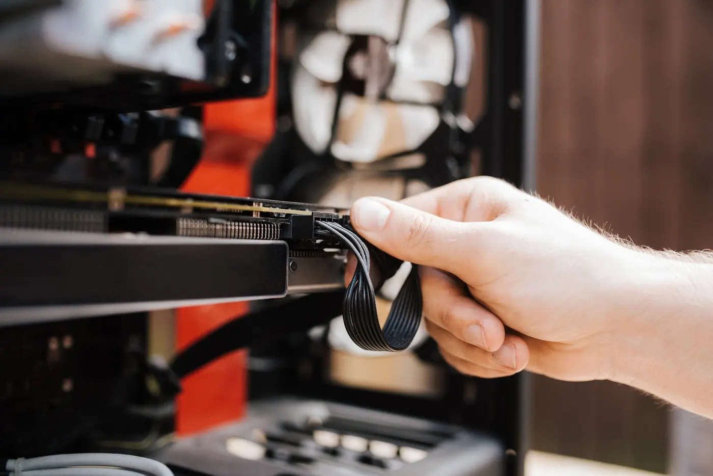 Mano che collega un cavo di alimentazione a una scheda dentro un PC.